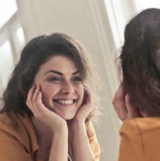 photo of woman looking at the mirror